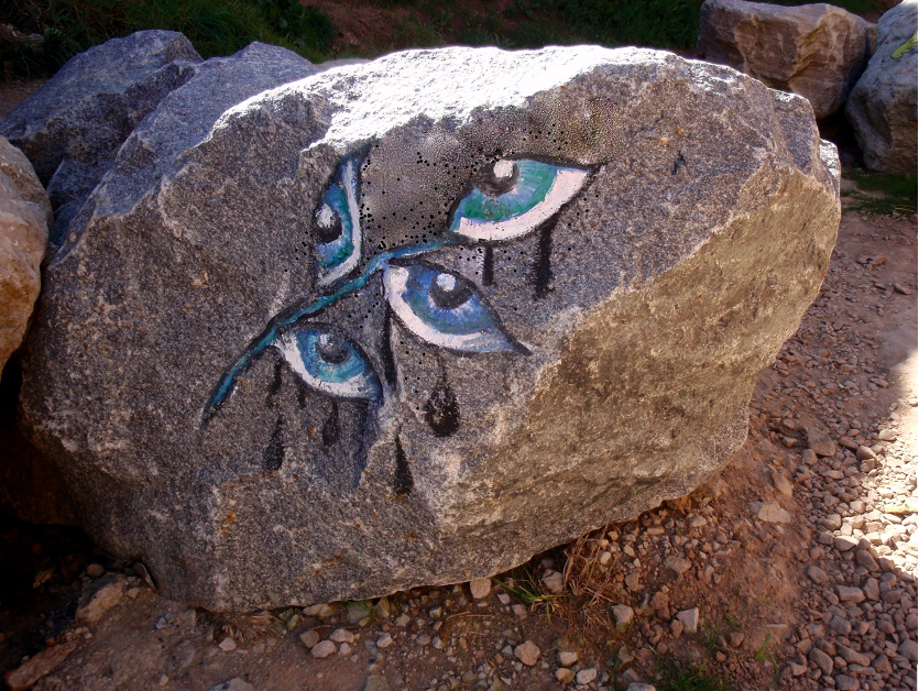 painting of crying eyes on rock