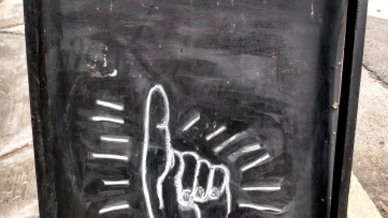 Blackboard standing on street with 'Tierra' written on it and hand drawn pointing upwards to it